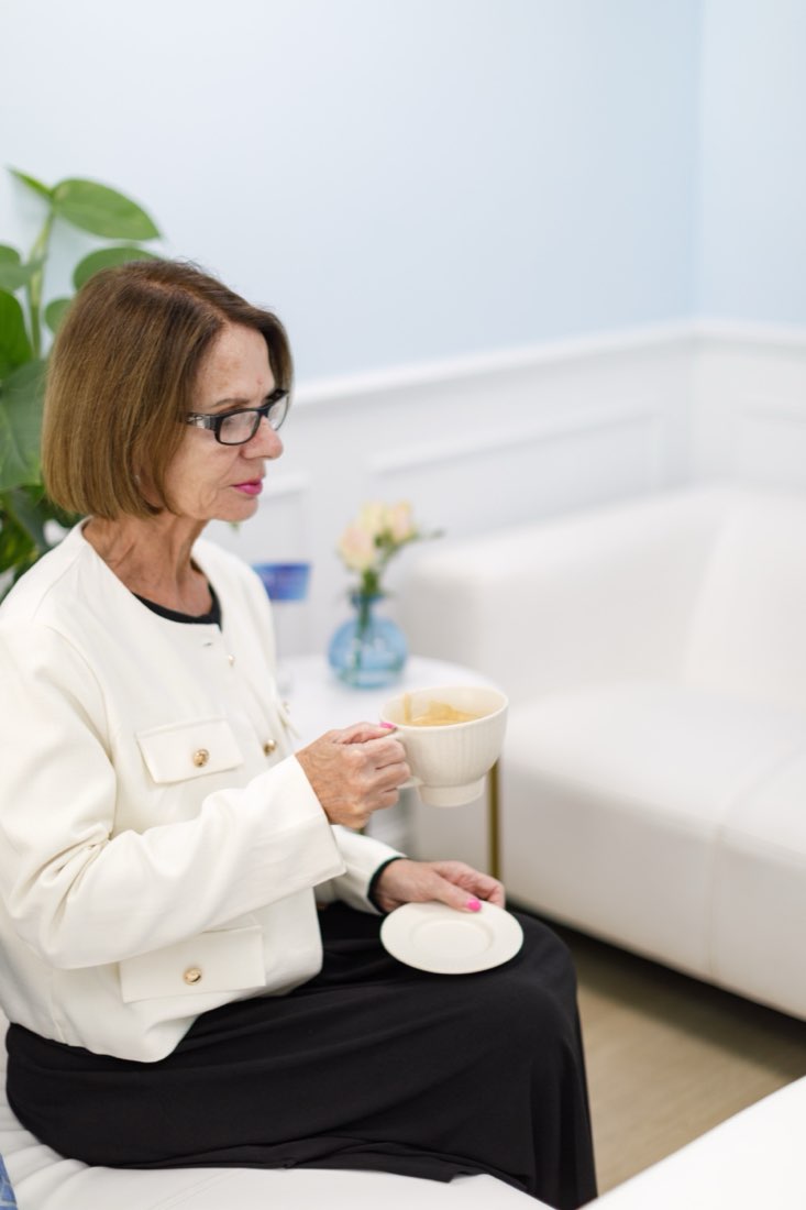 A client enjoys a coffee in the light-filled lounge at Cosmetic Medicine, Birchington