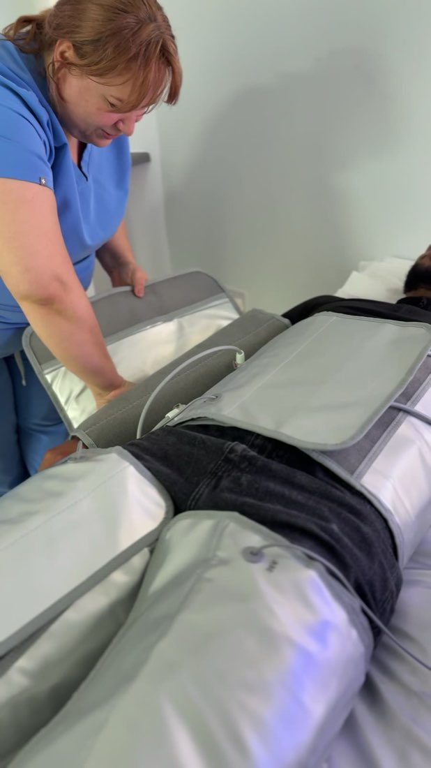 The pressotherapy suit being fastened around a client's waist