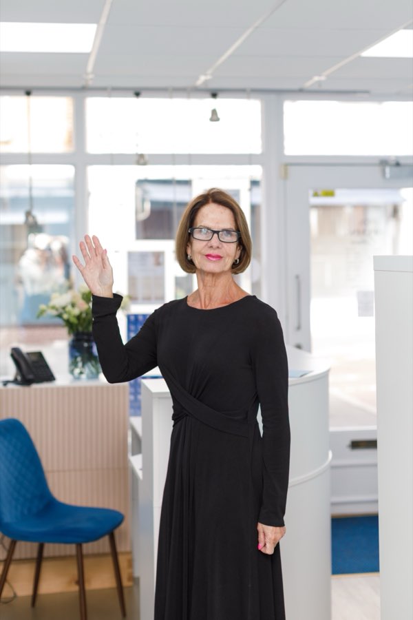 A client waves goodbye at reception after her appointment